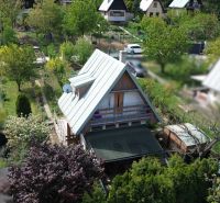 A cottage in Nové Vinohrady in Suchá nad Parnou surrounded by greenery and neighboring cottages.