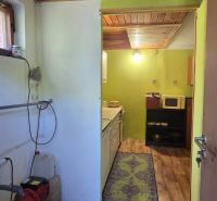 Interior of a cabin with a kitchen, wooden decor flooring, and furnishings.