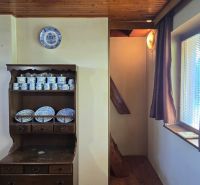 The interior of the cabin with a wood-patterned floor, wooden ceiling, and porcelain dishes.
