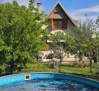 A cottage in Suchá nad Parnou, Nové Vinohrady, surrounded by greenery and a swimming pool.