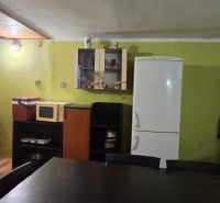 A kitchen in a cottage with green walls, a refrigerator, and a kitchen unit.