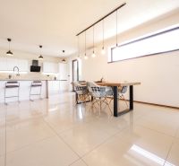 Kitchen in a family house with a dining table, bar stools, and light tiles.