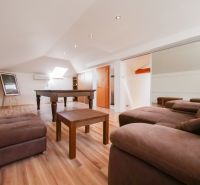 Living room in a family house with a pool table and a wooden decor floor.
