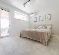 Bedroom in a family house with a light wall, bed, and air conditioning.