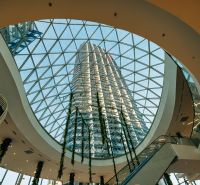 A spacious atrium with a glass roof and a tall building in the background.
