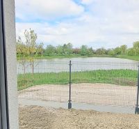 The view from a family house in Selice of an overgrown water surface and a fence.