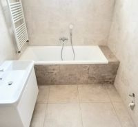Bathroom with a bathtub, sink, and ladder radiator in a family house.