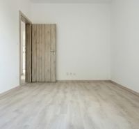 A room with a wooden decor floor and wooden doors in a family house.