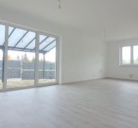 A spacious interior of a family house with large windows and a wooden decor floor.