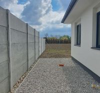 A family house in Selice with a concrete fence and gravel paving in the yard.