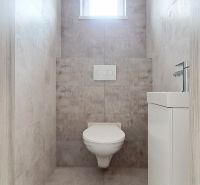 A toilet in a family house with tiles and a small window.