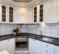 White kitchen with a dark countertop in a 3-room apartment, complemented by built-in appliances.