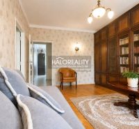 Living room with a bookshelf, sofa, and wooden decor flooring in a three-room apartment.