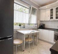 A kitchen in a 3-room apartment with white cabinets, a table, and four chairs.