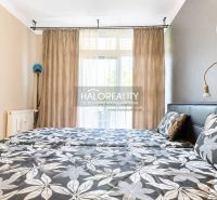 A bedroom in a 3-room apartment with floral patterned bed linen and curtains.