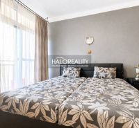Bedroom with patterned bedding in a 3-room apartment, next to a wardrobe and a lamp.