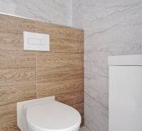 A toilet in the bathroom of a family house with marble and wooden tiles.