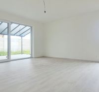 A spacious room with large windows and a wooden decor floor in a family house.