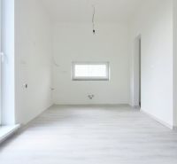 A room in a family house with white walls and a wooden decor floor.