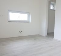 A room in a family house with a wooden decor floor and a small window.
