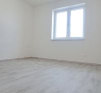 A room with a window and a wooden decor floor in a family house.