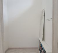 Narrow room with a distribution board in a family house, light tiles, neutral walls.
