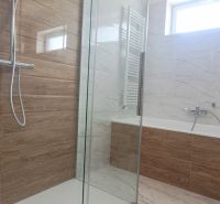A bathroom with a modern shower enclosure and a bathtub in a family house.