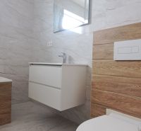 A bathroom in a family house with a sink, mirror, and floor with a wooden decor.