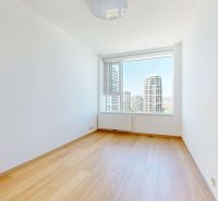 Bright room, large window, wooden decor flooring, city view.
