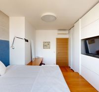 Bedroom in a 4-room apartment with a bed, wood-patterned flooring, and a TV on the wall.