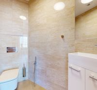 A bathroom with light tiles and a white sink in a 4-room apartment.