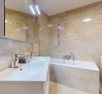 A bathroom in a 4-room apartment with a bathtub, two sinks, and a washing machine.