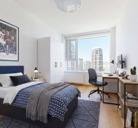 Bedroom with a bed, desk, and view in a 4-room apartment.