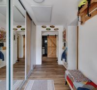 A hallway in a family house with a mirrored wardrobe and a floor with a wooden decor.