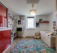 Children's room in a family house with a colorful carpet and a wooden decor floor.