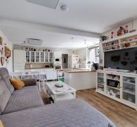 Living room in a family house with wood-patterned flooring, white furniture, and a sofa.