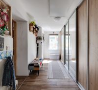 Hallway of a family house with coat hooks and a mirror, floor with wooden decor.