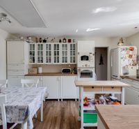 A kitchen in a family house with white furniture and a wooden decor floor.