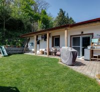 A family house in Potzneusiedl with a terrace, greenery, and a children's slide, surrounded by nature.