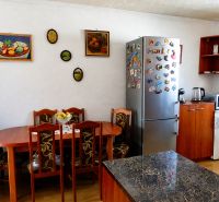 A kitchen in a 2-room apartment with a table, refrigerator, and wall decorations.