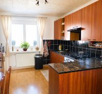 A kitchen in a 2-room apartment with a wooden decor floor and dark tiles.