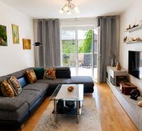 Living room in a two-room apartment with a wooden decor floor and a large sofa.
