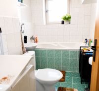 A bathroom with a bathtub and a sink in a 2-room apartment, tiled walls.