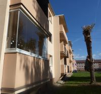 An apartment building with balconies and trimmed trees in Žiar nad Hronom, suitable for a 2-room apartment.