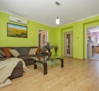 Living room with a corner sofa, glass table, and wooden decor flooring.