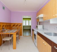 A kitchen with purple walls, a dining table, and a kitchen unit in a two-room apartment.