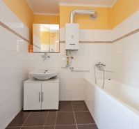 Bathroom in a two-room apartment with light tiles and white sanitary ware.