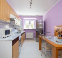 A kitchen in a 2-room apartment with purple walls, wooden decor, and a dining table.