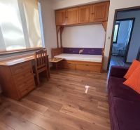 A room in a 3-room apartment with wooden decor, cabinets, and a couch.