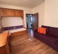 A room in a 3-room apartment with a wooden decor floor and a rainy view from the window.